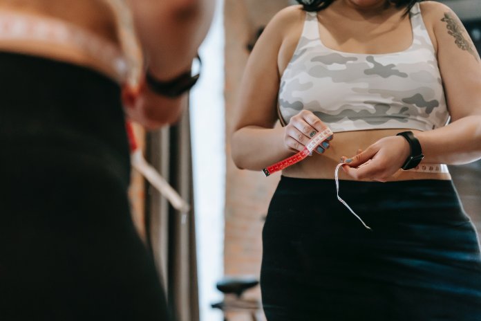 personne mesurant son tour de taille avec un mètre